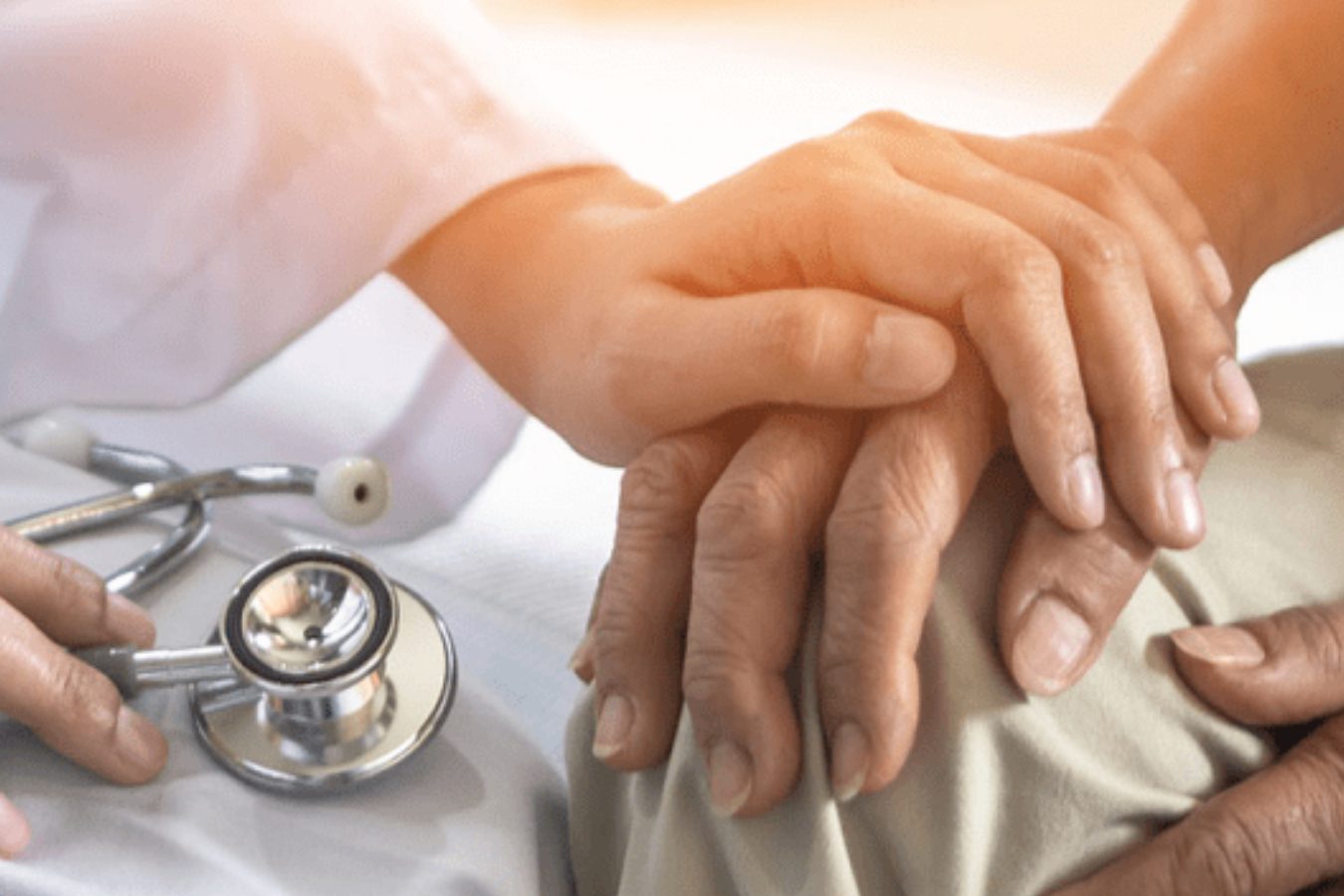 A compassionate doctor gently holds the hand of an elderly patient, symbolizing care and support in a medical setting.